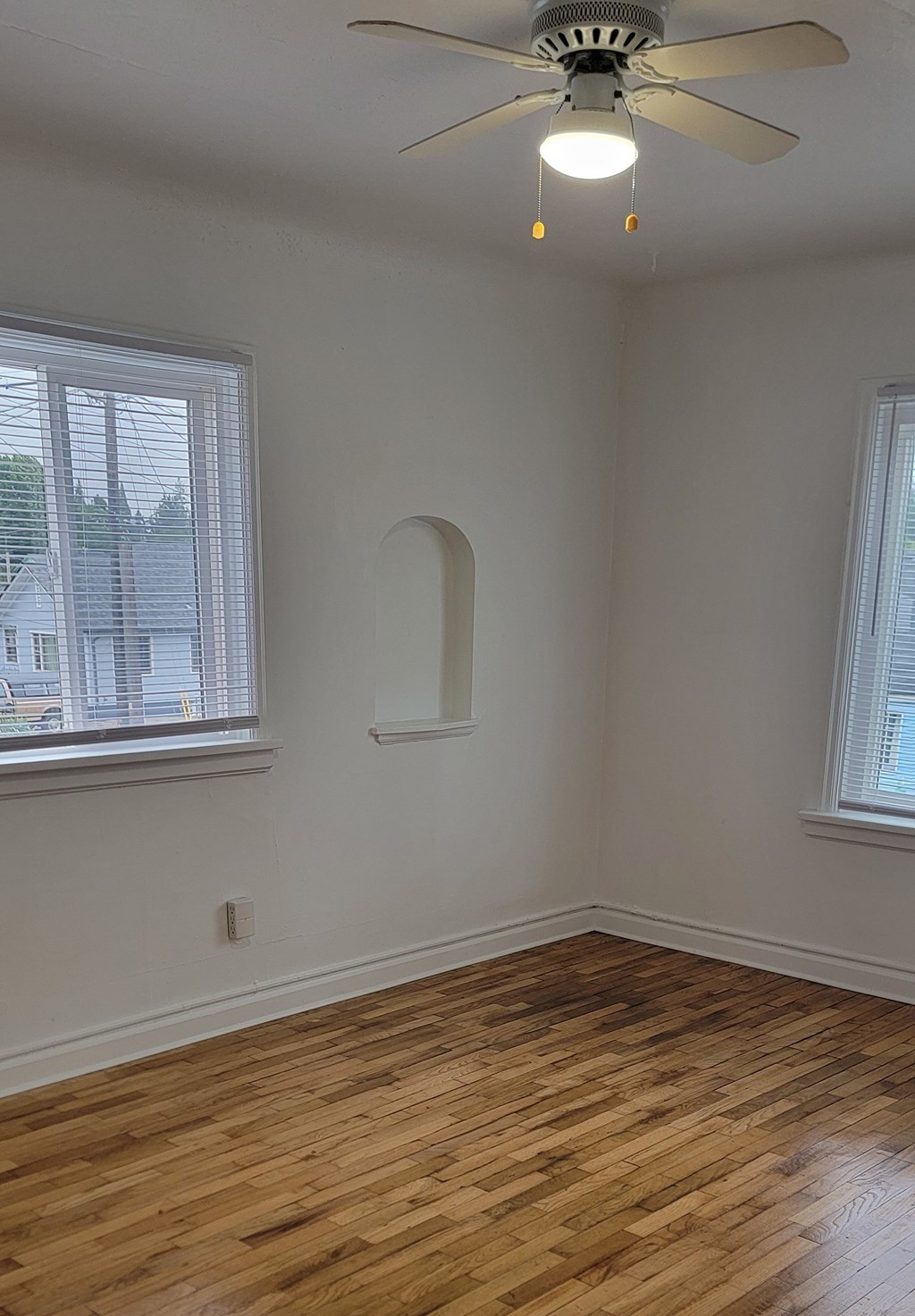 A room with a ceiling fan and wood flooring.