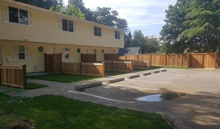 A building with a wooden fence and a paved area in front.