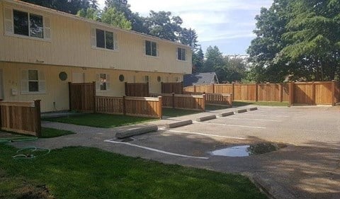 A building with a wooden fence and a paved area in front.