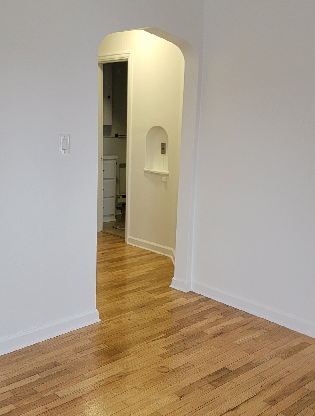 A hallway with a wooden floor and white walls.