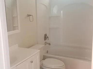 A white toilet sits next to a bathtub in a bathroom.