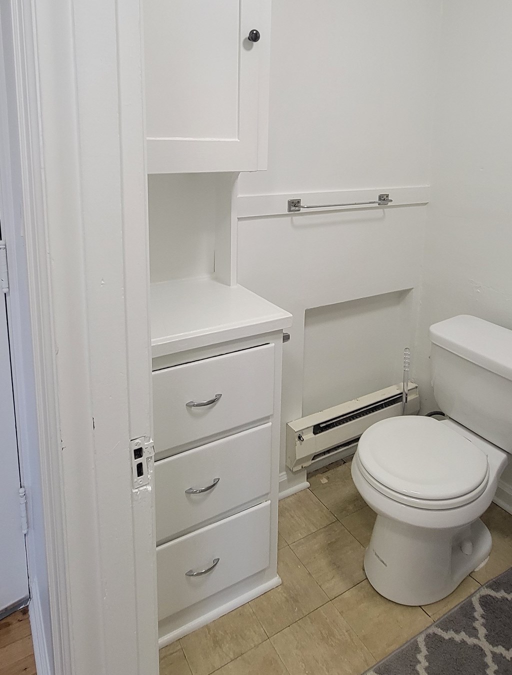 A white toilet in a bathroom with a cabinet above it.