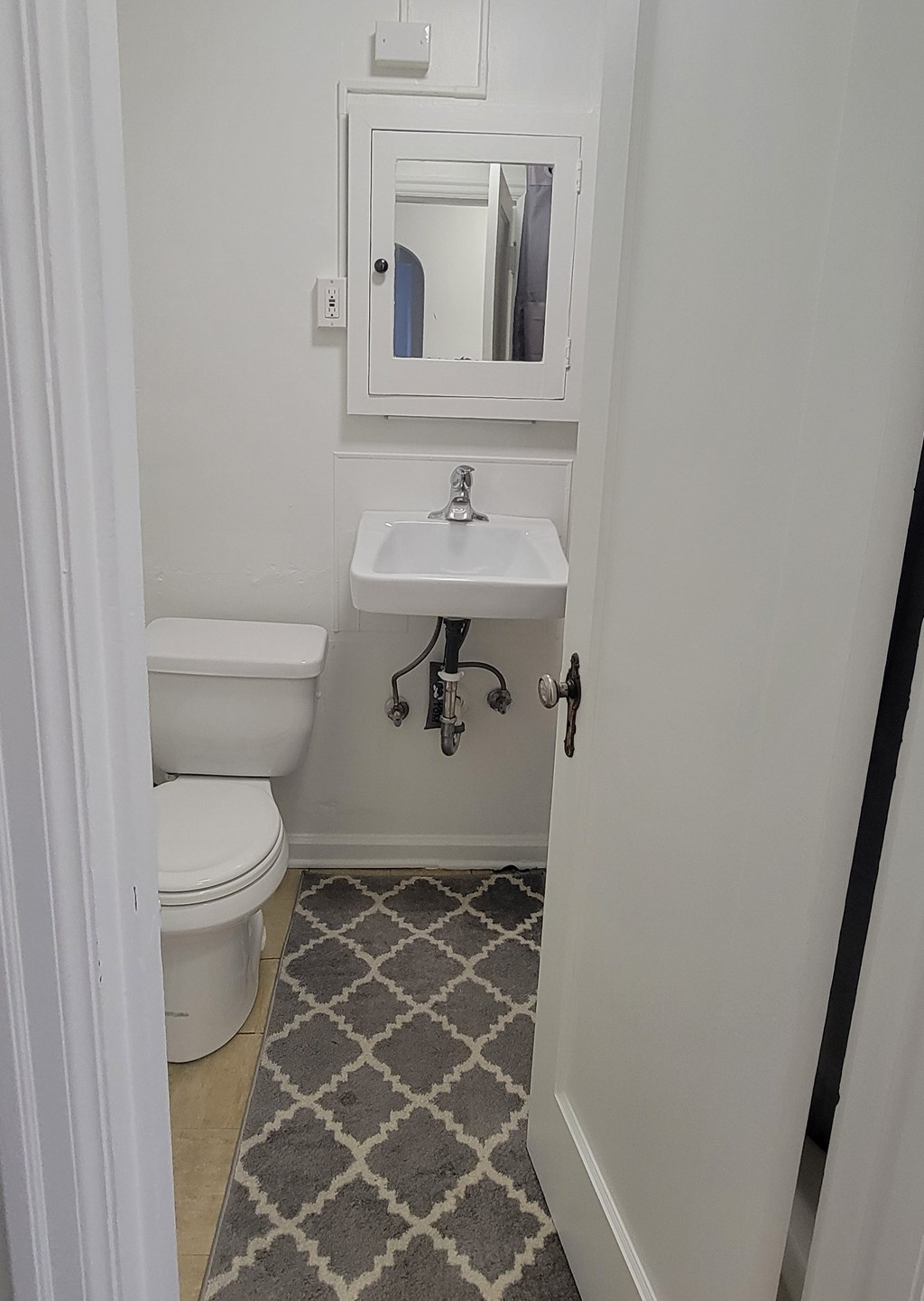 A bathroom with a toilet, sink and mirror.