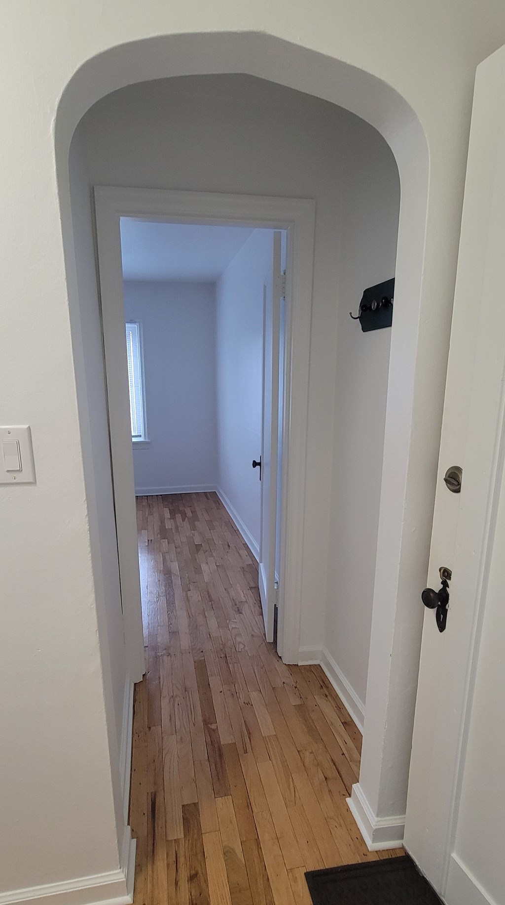 A hallway with a wooden floor and white walls.