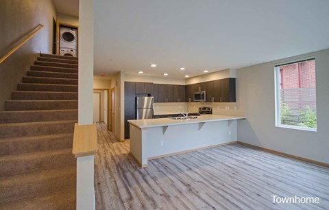 A spacious kitchen and living room with a staircase on the left side at Spyglass Hill Apartments, Bremerton, WA 98337
