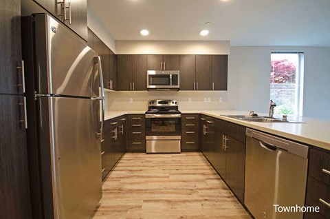 A kitchen with a stainless steel refrigerator and wooden floors at Spyglass Hill Apartments, Bremerton, WA 98337