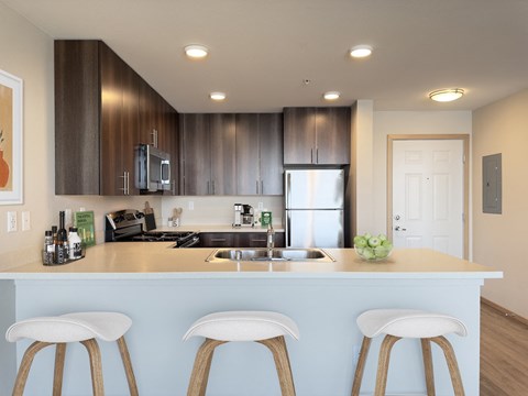a kitchen with a counter top with three stools at Spyglass Hill Apartments, Bremerton