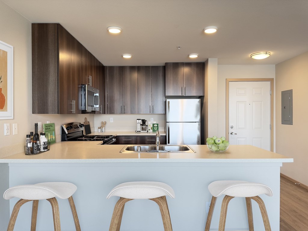 a kitchen with a counter top with three stools a kitchen with a counter top with three stools at Spyglass Hill Apartments, Bremerton