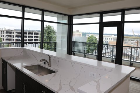 A kitchen with a marble countertop and a stainless steel sink.