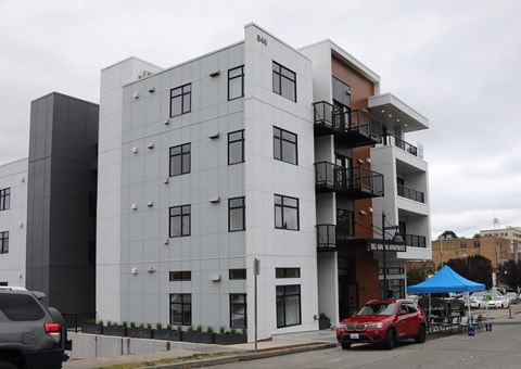 A modern multi-story building with a red car parked in front.
