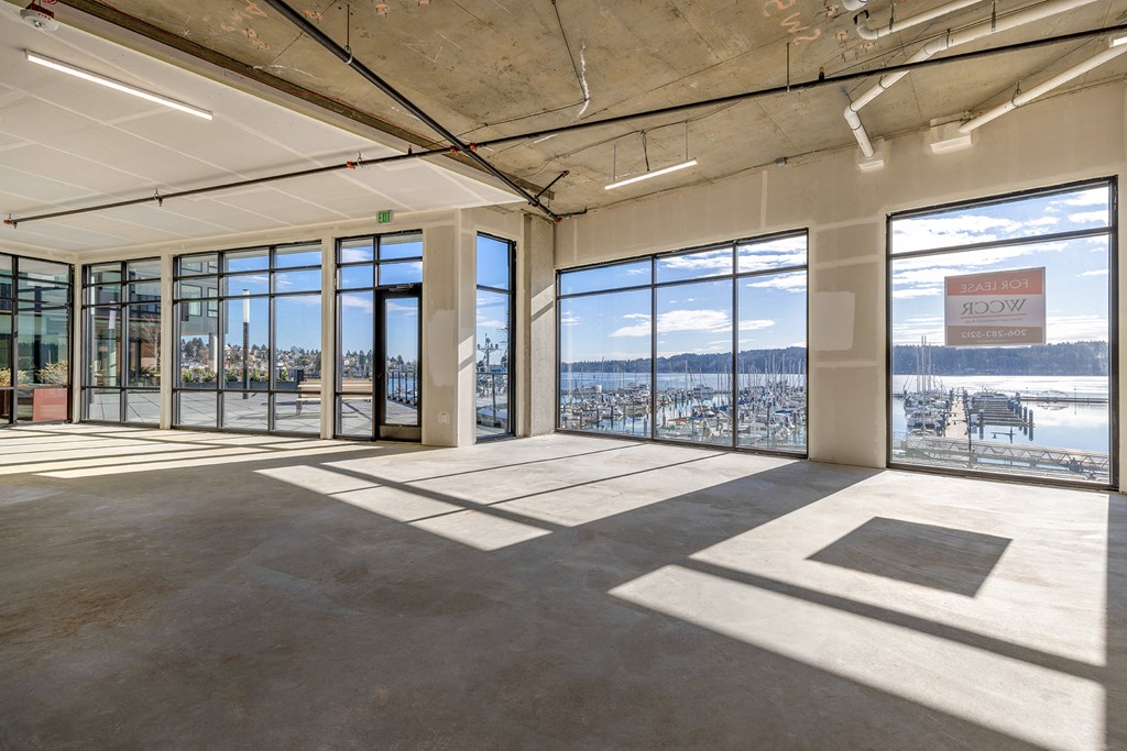 an empty room with floor to ceiling windows and a view of the water at Marina Square, Bremerton