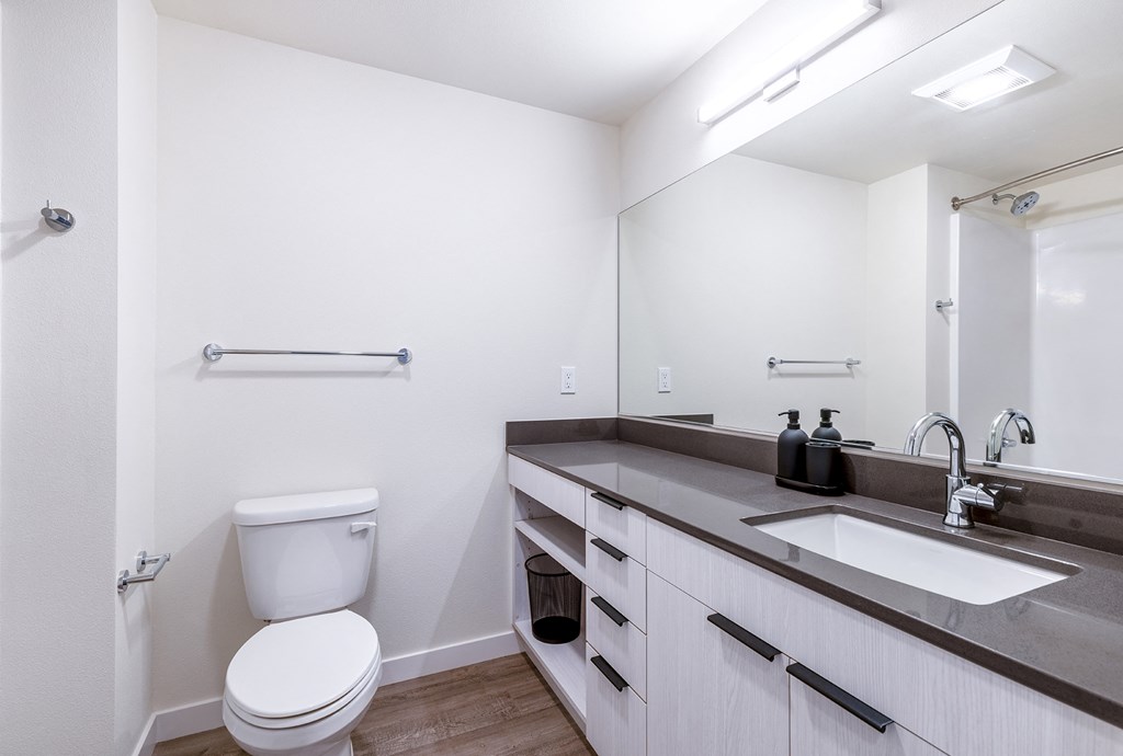 a bathroom with white walls and a large mirror at Marina Square, Bremerton