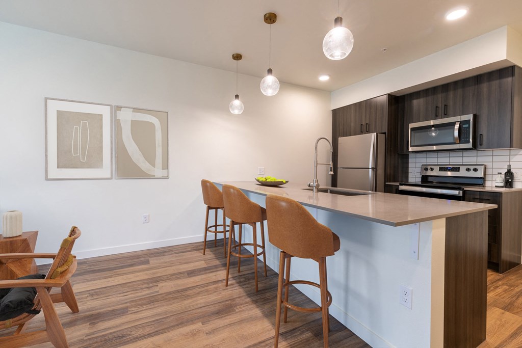 a kitchen with a large island with three stools in front of a counter top at Rivulet, Silverdale, WA