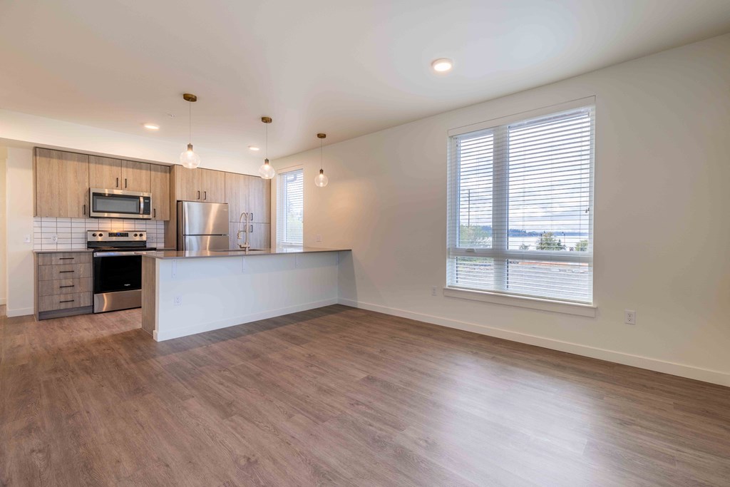 an empty living room with a kitchen and a large window at Rivulet, Washington, 98383