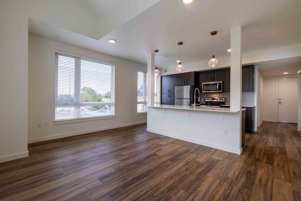 an empty living room with a kitchen and a large window at Rivulet, Silverdale, WA