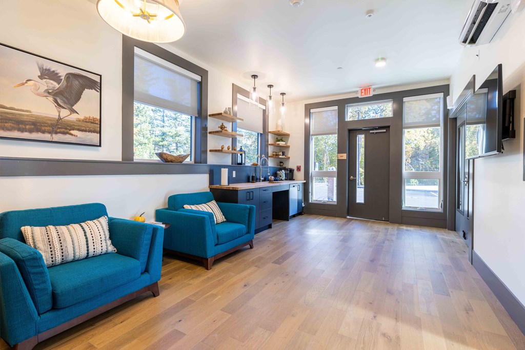 a living room with blue couches and a kitchen with a large window at Rivulet, Silverdale, 98383