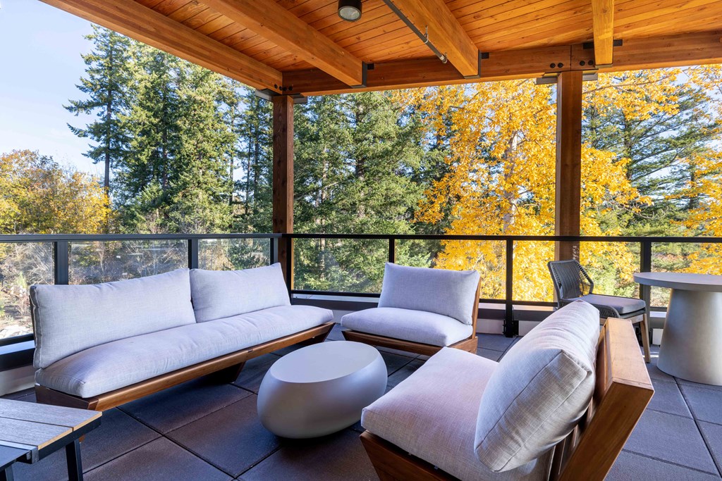 a covered porch with couches and chairs and a view of trees at Rivulet, Silverdale, 98383