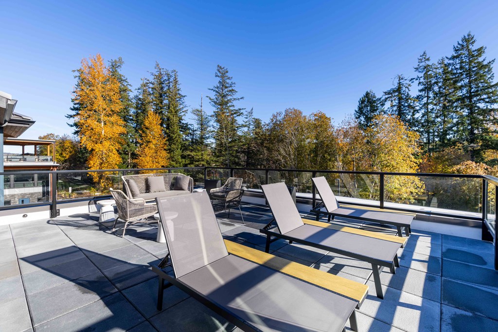 a patio with chairs and tables on a balcony with trees at Rivulet, Silverdale, 98383