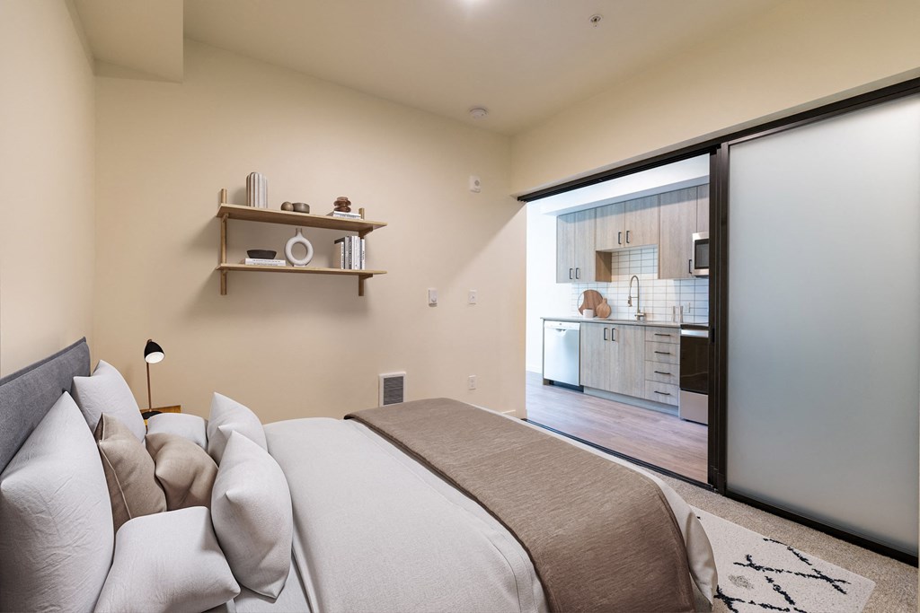a bedroom with a bed and a sliding glass door to a kitchen at Rivulet, Silverdale, 98383