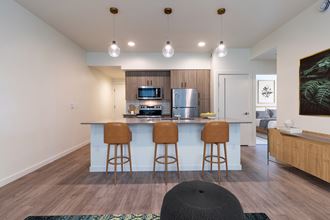 a kitchen with a bar and stools in a living room with a kitchen island