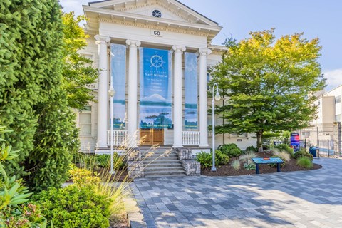 A white building with a banner on the front and a tree in front of it at Spyglass Hill Apartments, Bremerton, 98337