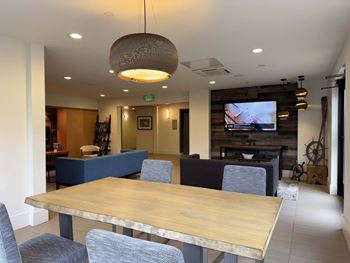 A large wooden table is surrounded by grey chairs in a well-lit room  at Spyglass Hill Apartments, Bremerton, 98337