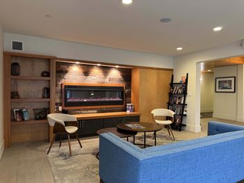 A living room with a blue couch, a wooden entertainment center, and a fireplace  at Spyglass Hill Apartments, Bremerton, 98337