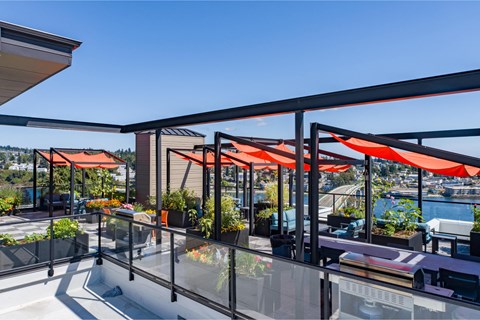 a terrace with orange umbrellas and tables on a balcony overlooking the water at Spyglass Hill Apartments, Bremerton, WA