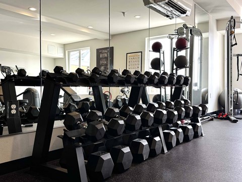 A gym with a rack of dumbbells and a mirror  at Spyglass Hill Apartments, Bremerton, 98337