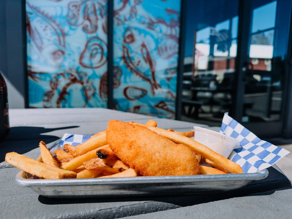 a plate of fish and chips on a table with graffiti in the background at Rivulet, Silverdale