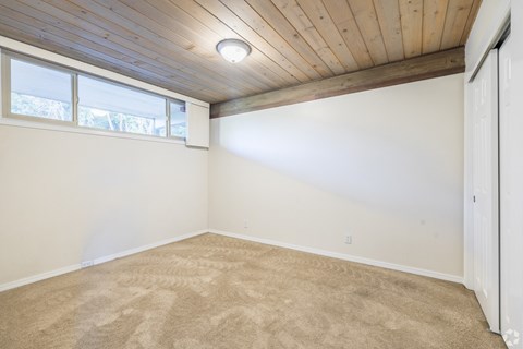 A room with a wooden ceiling and carpeted floor.