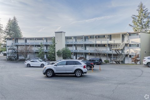 A parking lot with cars and a building in the background.