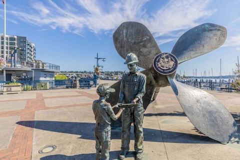 A statue of a man and a child are standing in front of a large propeller  at Spyglass Hill Apartments, Bremerton, 98337