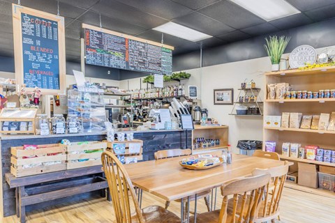A coffee shop with a wooden table and chairs in the foreground  at Spyglass Hill Apartments, Bremerton, 98337
