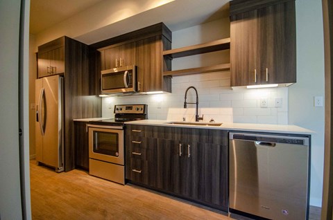 A modern kitchen with dark wood cabinets and stainless steel appliances at B Flats Apartments, Bremerton, Washington