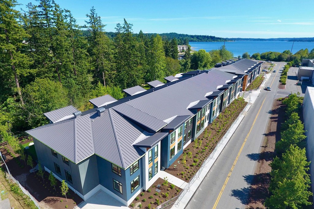 an aerial view of a building with a metal roof and a lake in the background at Rivulet, Silverdale, 98383