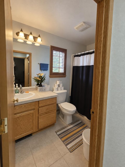A bathroom with a toilet, sink, and mirror.