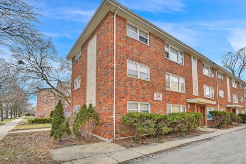 a brick apartment building with a sidewalk in front of it