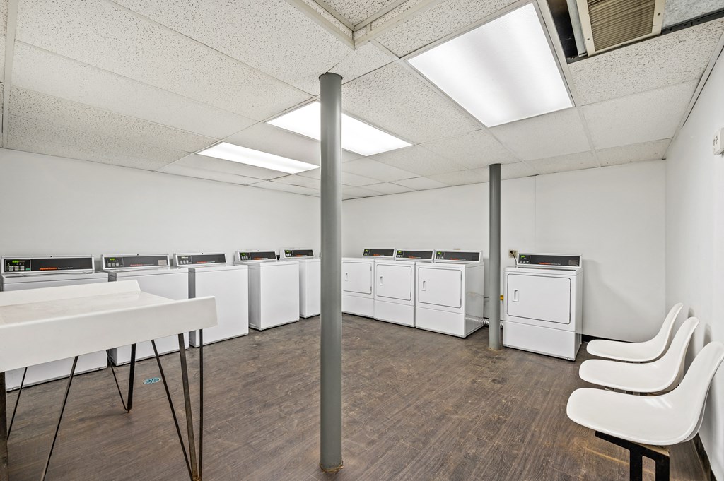 a room filled with washers and dryers and a table with chairs