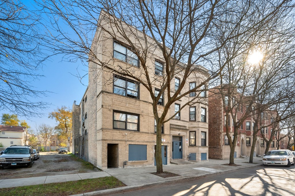 a brick apartment building on a city street with trees