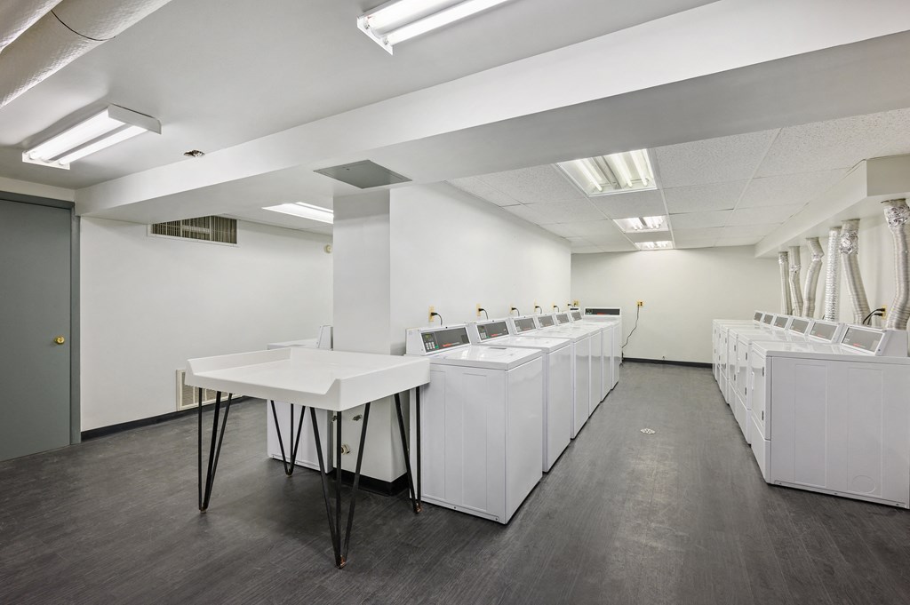 a large room with white tables and sinks in it