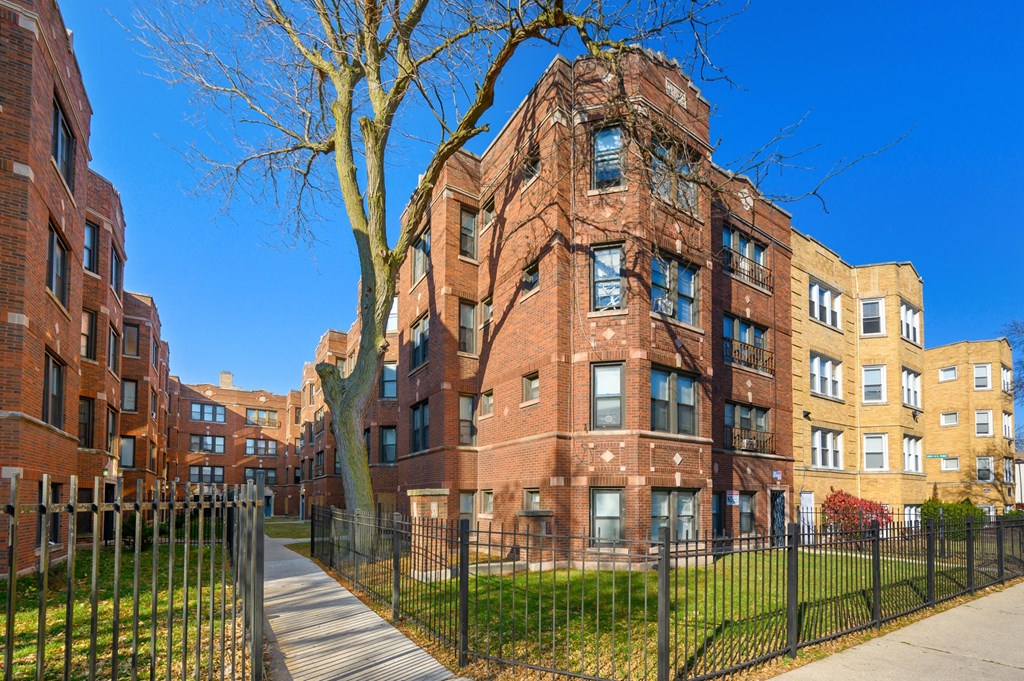 a brick building with a sidewalk and a fence in front of it