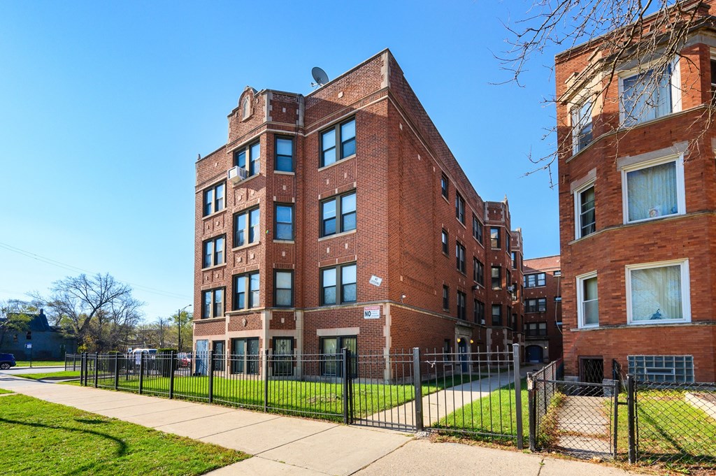 a brick building with a sidewalk and a fence in front of it