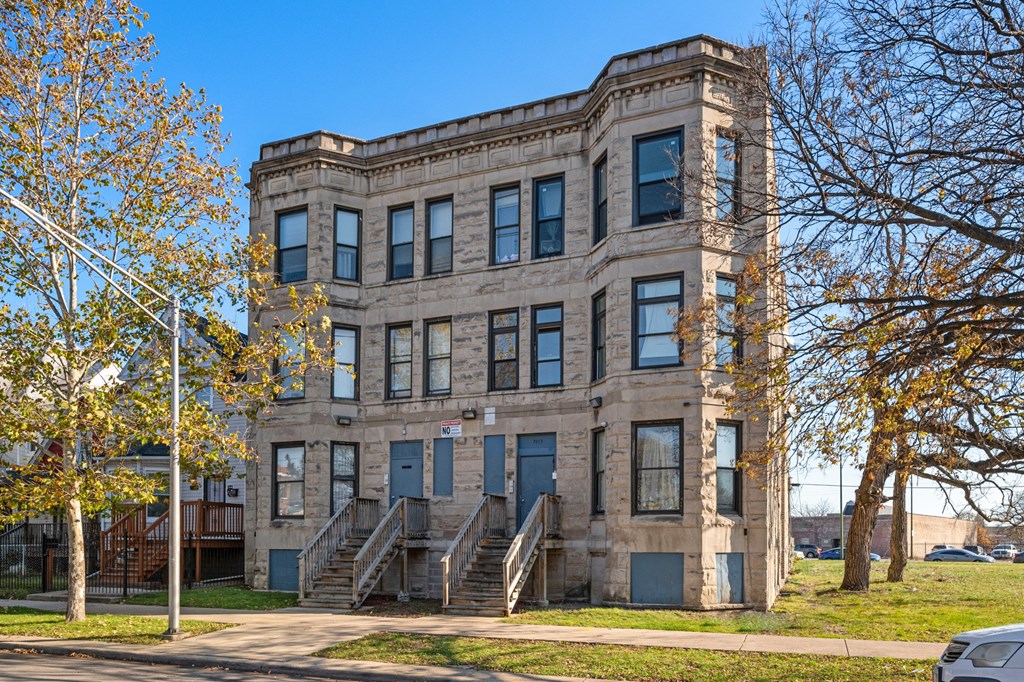 an old brick building with stairs and trees in front of it