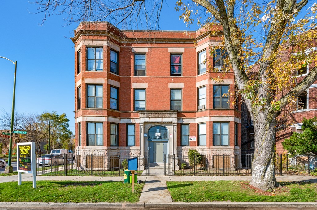 a brick building with a blue door and a tree in front of it