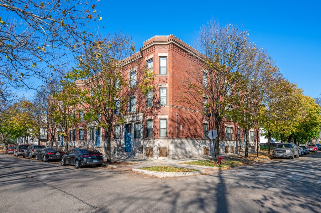 a brick building on the corner of a street with cars parked