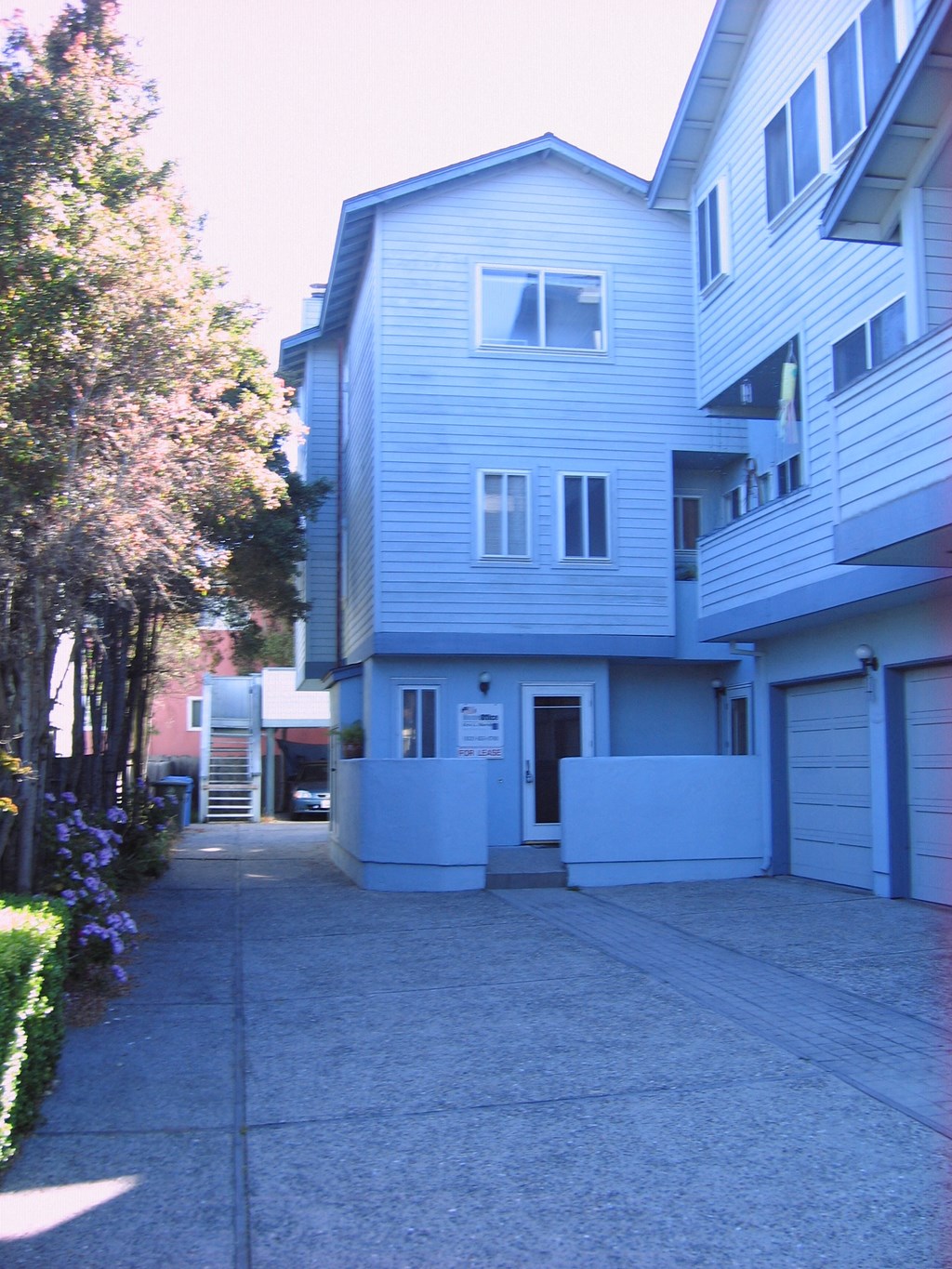 a blue and white apartment building with a sidewalk