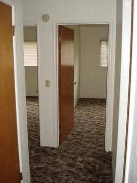 a hallway with an open door and a door to a bedroom