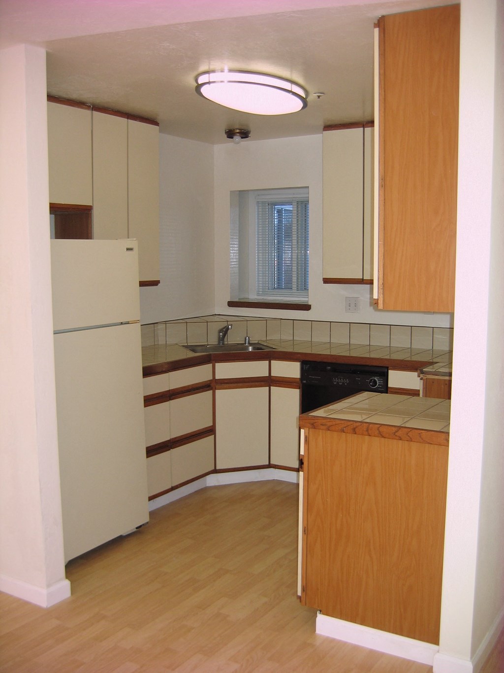 an empty kitchen with white cabinets and a refrigerator
