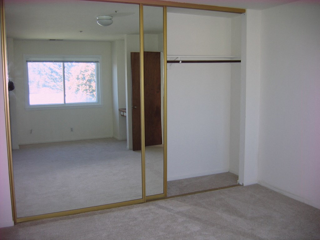 an empty room with a closet and a window